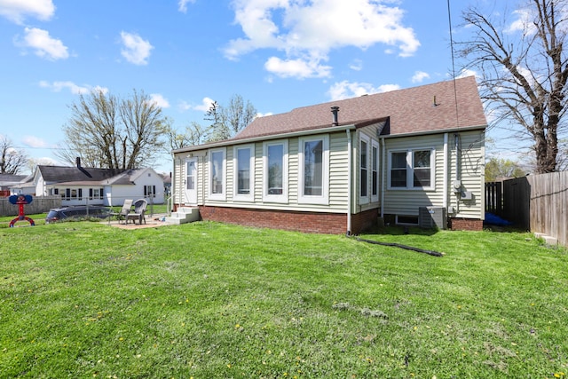 rear view of house with a yard, a fenced backyard, entry steps, a patio, and a shingled roof