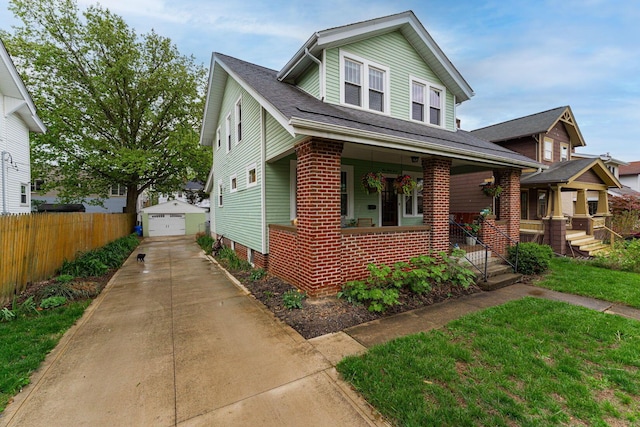view of front of property featuring a porch, fence, a detached garage, an outdoor structure, and brick siding