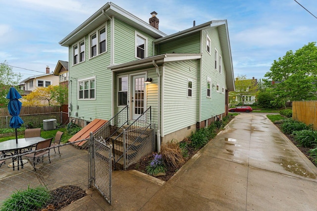 view of front of property with a patio, fence, a chimney, driveway, and entry steps