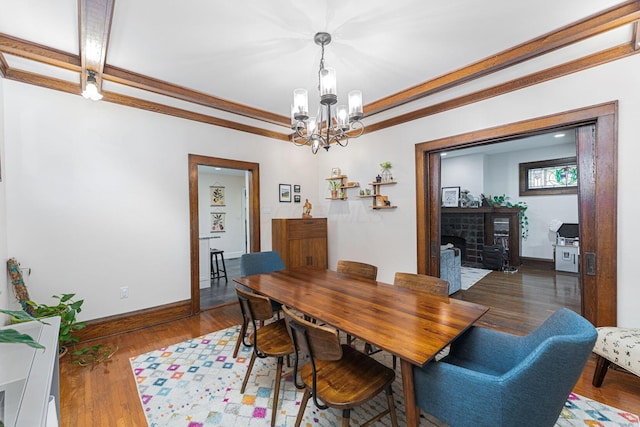 dining room with wood finished floors, baseboards, ornamental molding, and a notable chandelier