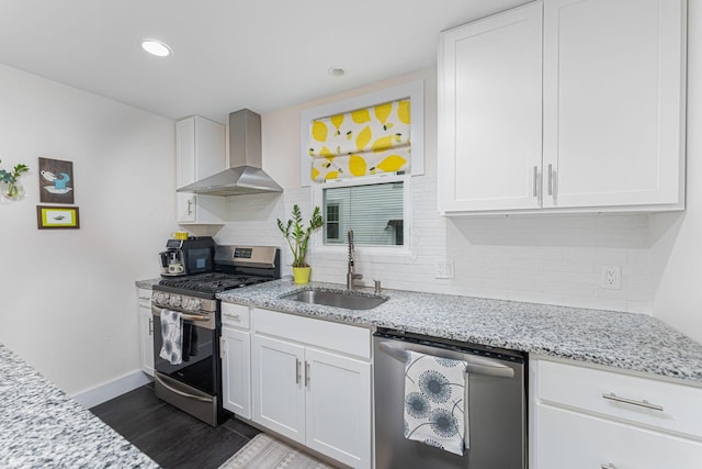 kitchen featuring a sink, stainless steel appliances, wall chimney range hood, and white cabinets