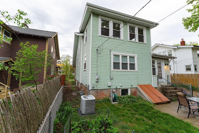 rear view of property with a fenced backyard, a patio, and cooling unit