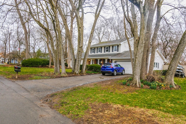 view of front of house featuring aphalt driveway, an attached garage, a front yard, and roof with shingles