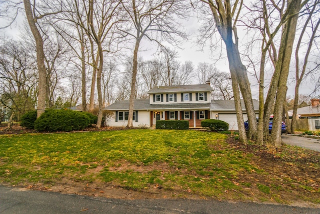 view of front of house with driveway, a porch, a front yard, a garage, and a chimney