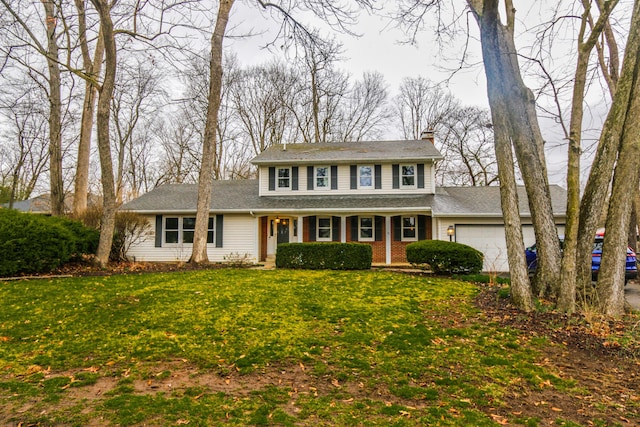 colonial home featuring a chimney, a front lawn, and a garage