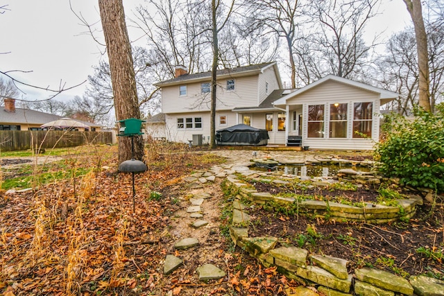 rear view of house with a sunroom, a chimney, and fence