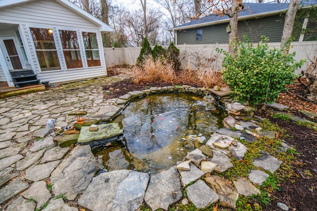 view of yard with a garden pond, fence, entry steps, and a hot tub