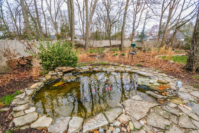 view of swimming pool with a garden pond and a fenced backyard