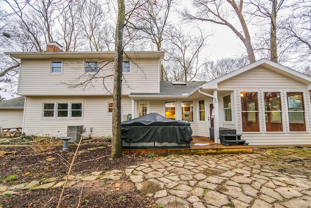 rear view of house featuring cooling unit, entry steps, a chimney, and a patio area
