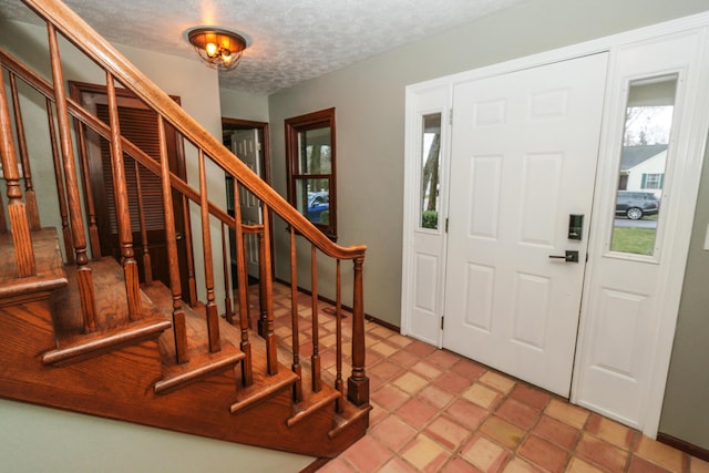 foyer entrance featuring stairway and a textured ceiling
