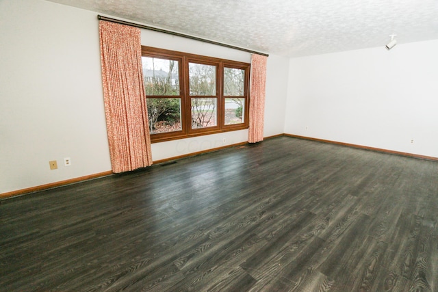 unfurnished room with visible vents, a textured ceiling, baseboards, and wood finished floors