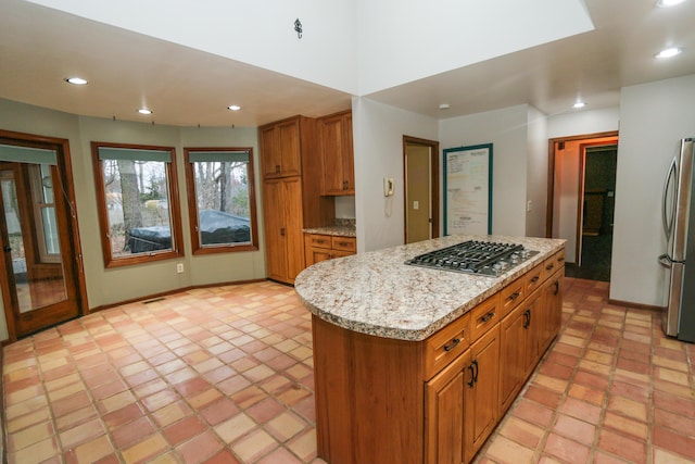 kitchen featuring brown cabinetry, light stone countertops, a kitchen island, recessed lighting, and stainless steel appliances