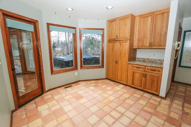 kitchen featuring recessed lighting, visible vents, light stone countertops, and baseboards