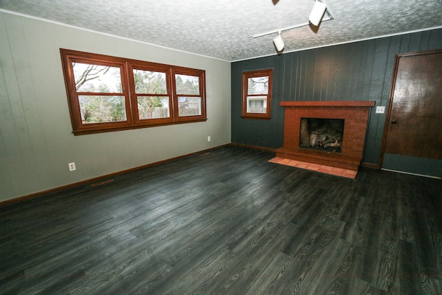unfurnished living room with baseboards, a textured ceiling, a brick fireplace, and wood finished floors