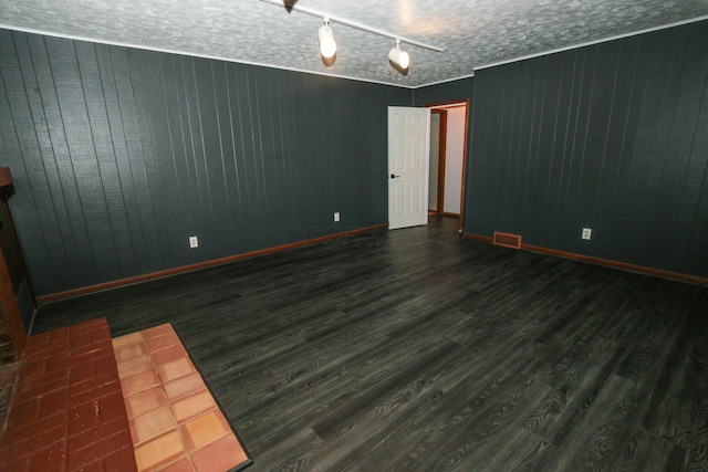 spare room featuring visible vents, a textured ceiling, baseboards, and wood finished floors