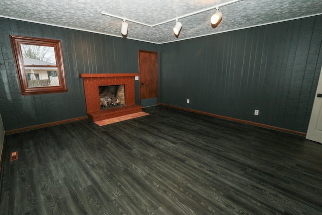 unfurnished living room featuring a fireplace, wood finished floors, baseboards, and a textured ceiling