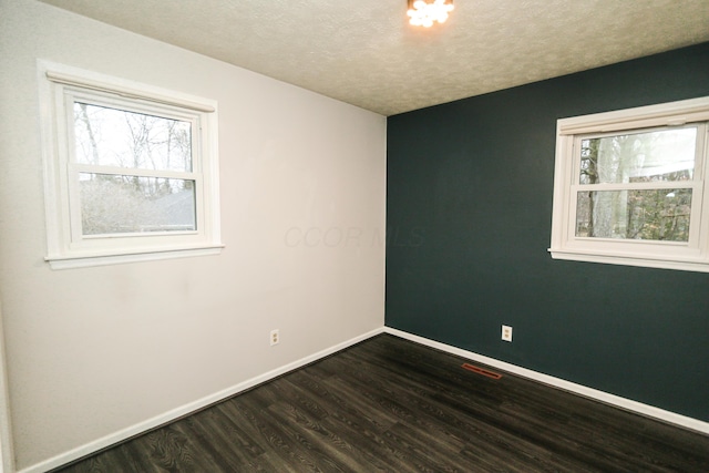 unfurnished room featuring visible vents, a textured ceiling, baseboards, and dark wood-style flooring