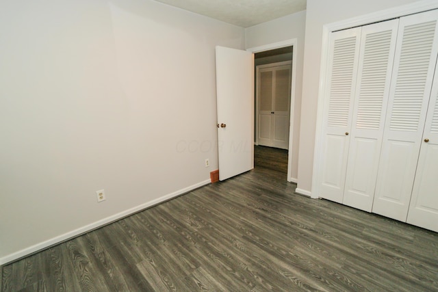 unfurnished bedroom featuring wood finished floors, baseboards, and a closet