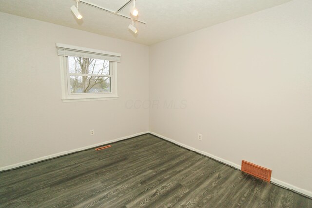 empty room featuring dark wood-type flooring, baseboards, and visible vents