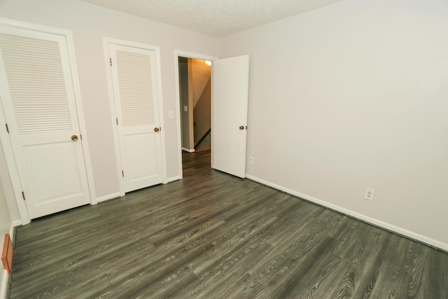 unfurnished bedroom featuring dark wood-type flooring and baseboards