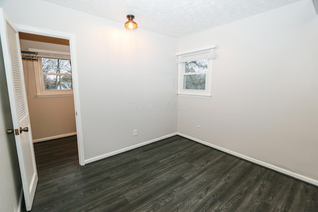 empty room with baseboards, dark wood-style flooring, and a textured ceiling
