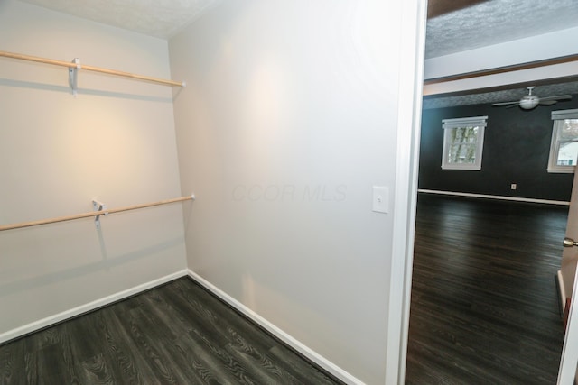 spacious closet with dark wood-style floors and ceiling fan