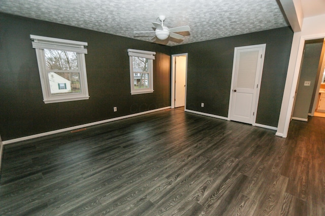 unfurnished bedroom with multiple windows, a textured ceiling, baseboards, and dark wood-style flooring