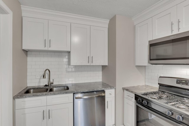 1333 Carolyn Ave, Columbus, OH 43224 - kitchen with dark stone countertops, a sink, a textured ceiling, white cabinetry, and stainless steel appliances