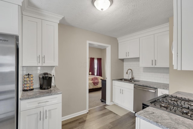 1333 Carolyn Ave, Columbus, OH 43224 - kitchen with a textured ceiling, white cabinets, a sink, stainless steel appliances, and light wood finished floors