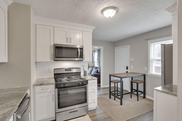 1333 Carolyn Ave, Columbus, OH 43224 - kitchen featuring tasteful backsplash, light wood-style floors, white cabinets, and stainless steel appliances