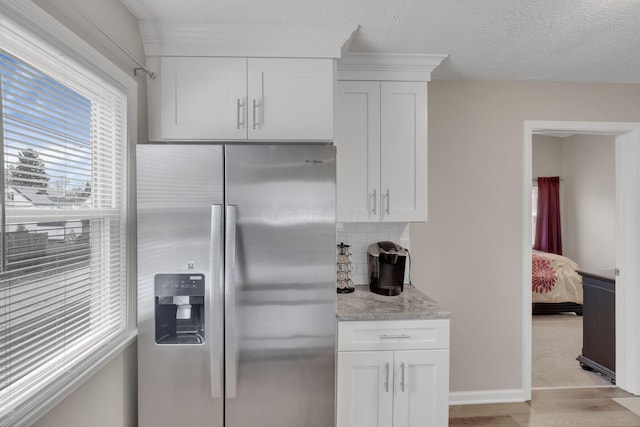 1333 Carolyn Ave, Columbus, OH 43224 - kitchen with white cabinets, stainless steel refrigerator with ice dispenser, light stone countertops, and backsplash