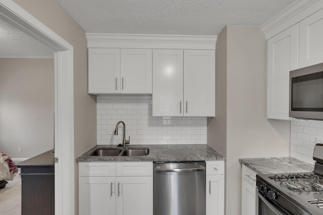 1333 Carolyn Ave, Columbus, OH 43224 - kitchen with dark stone countertops, white cabinetry, backsplash, appliances with stainless steel finishes, and a sink