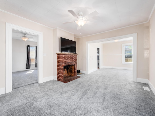 unfurnished living room featuring ceiling fan, carpet floors, crown molding, and a brick fireplace