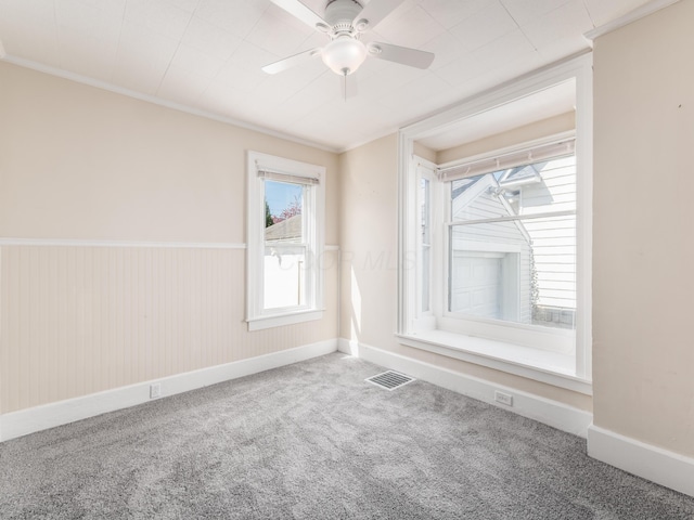 unfurnished room featuring carpet floors, ceiling fan, baseboards, visible vents, and crown molding