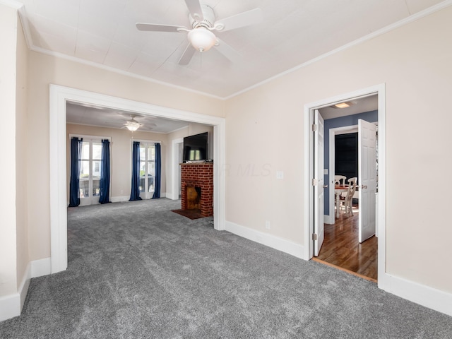 unfurnished living room with ornamental molding, ceiling fan, carpet flooring, a brick fireplace, and baseboards