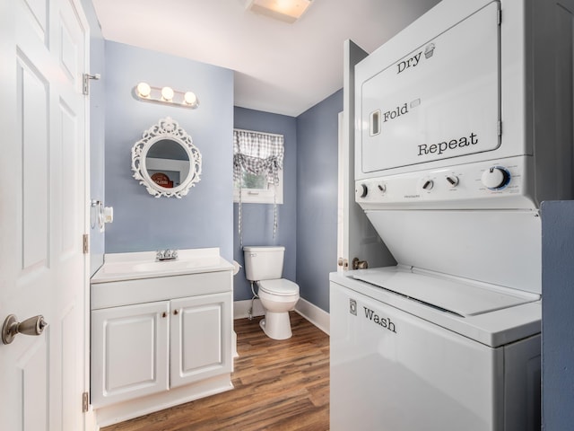 half bath with vanity, toilet, baseboards, stacked washer / dryer, and wood finished floors