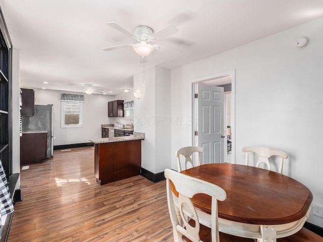 dining room with ceiling fan, baseboards, and light wood-style floors