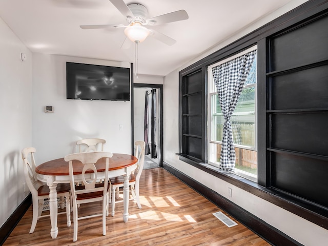 dining space featuring visible vents, a ceiling fan, light wood finished floors, and baseboards