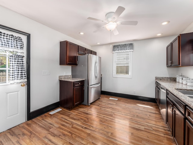 kitchen with appliances with stainless steel finishes, light wood-style floors, a ceiling fan, baseboards, and dark brown cabinets