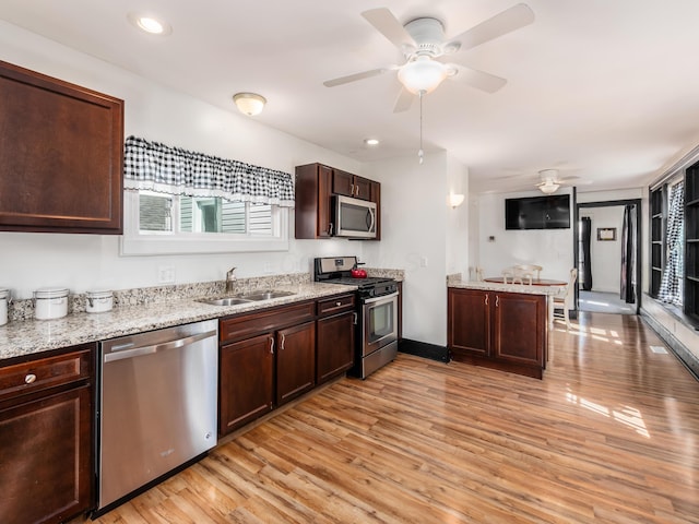 kitchen with light wood-style flooring, a sink, stainless steel appliances, dark brown cabinets, and a ceiling fan