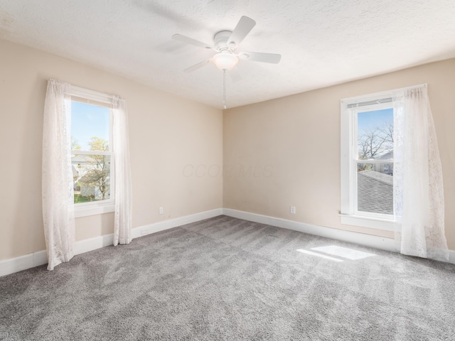 spare room with baseboards, ceiling fan, a wealth of natural light, and carpet