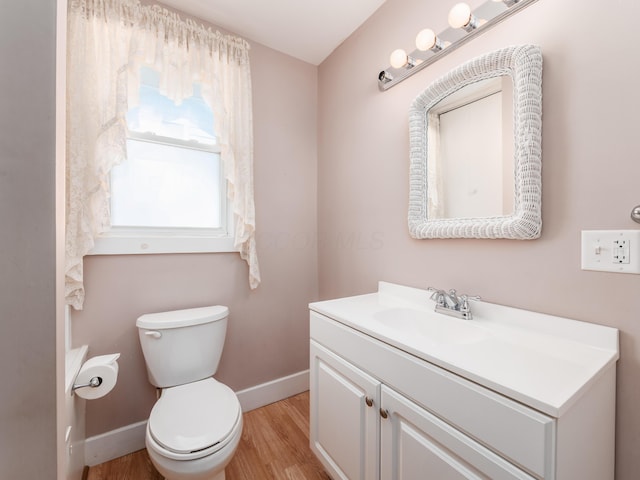 bathroom featuring toilet, baseboards, wood finished floors, and a healthy amount of sunlight