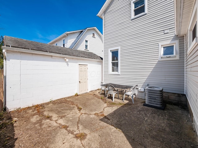 exterior space featuring a patio, cooling unit, and roof with shingles