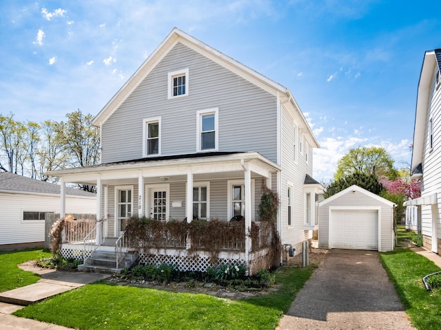 view of front of home with aphalt driveway, a detached garage, an outbuilding, a front yard, and a porch