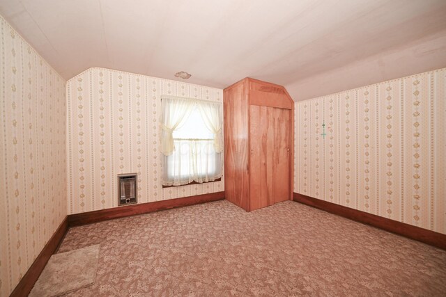 additional living space featuring heating unit, baseboards, carpet floors, wallpapered walls, and lofted ceiling