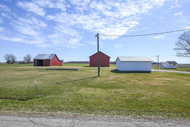 view of yard featuring an outbuilding, a detached garage, driveway, and a pole building