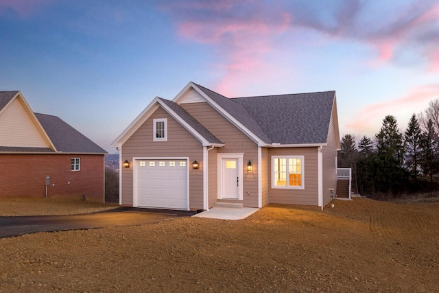 view of front facade featuring aphalt driveway, a garage, and roof with shingles
