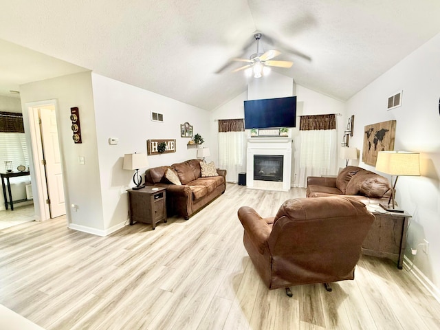 living area with ceiling fan, vaulted ceiling, light wood-style flooring, and visible vents