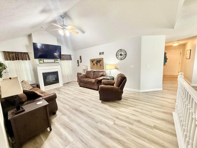 living area with light wood finished floors, a ceiling fan, baseboards, lofted ceiling, and visible vents