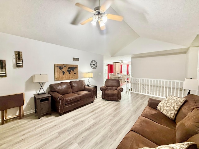 living area featuring visible vents, wood finished floors, lofted ceiling, baseboards, and a ceiling fan